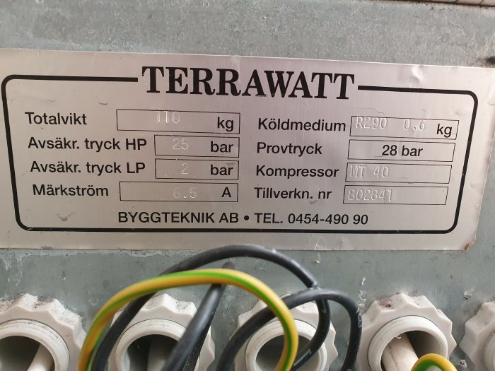 Etikett på en värmepump med modellnamnet "TERRAWATT" och specifikationer som totalvikt, tryckvärden och kylmedium.