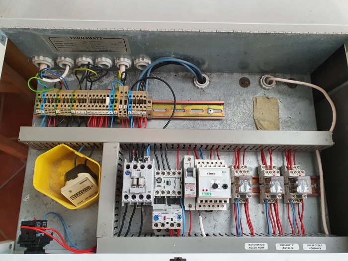 Intern komponentvy av äldre Terrawatt bergvärmepump med ledningspanel och säkringar.