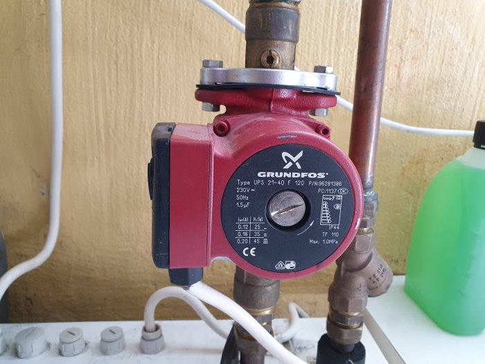 Grundfos cirkulationspump installerad i värmesystem, med kopparledningar och inställningsreglage.