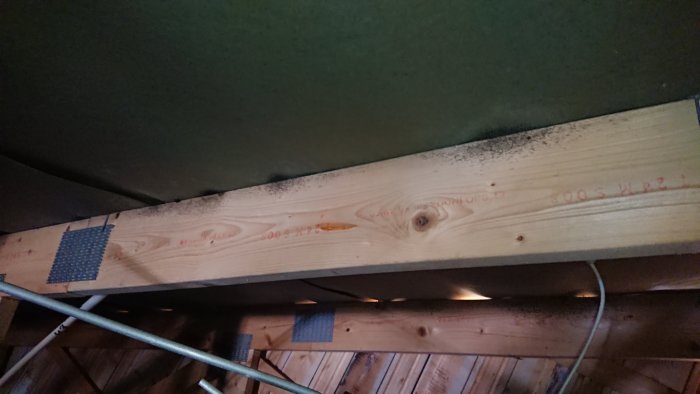 Takstol med svarta mögelprickar nära ventilationsgaller på vinden.