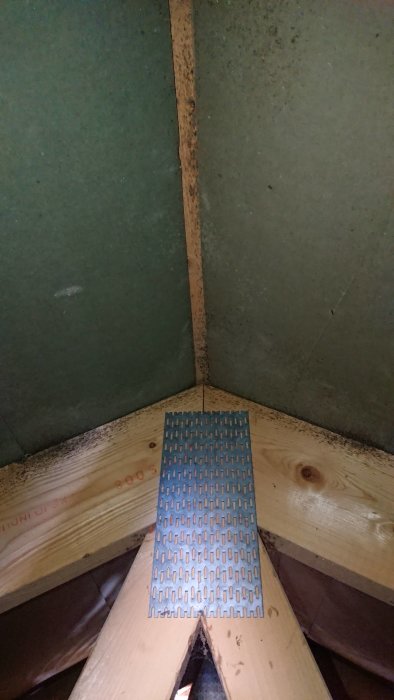 Takstolar i en vind med svarta prickar nära ventiler som antyder fuktskador, samt en ventilerande bräda i förgrunden.