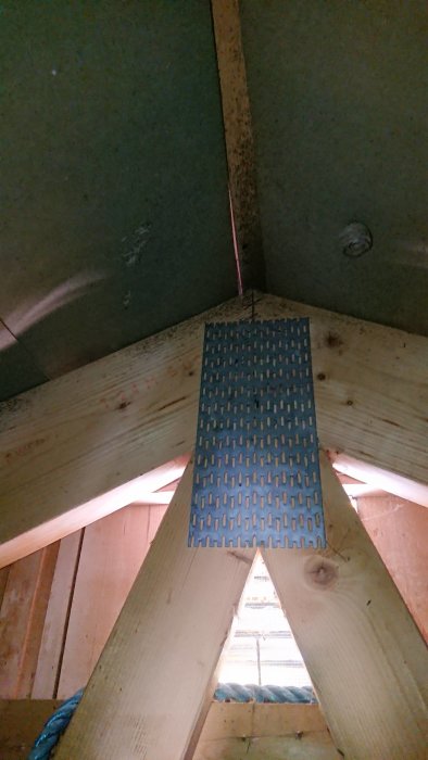 Takstolar i en vind med svarta prickar som tyder på fuktskador nära ett metallventilationsgaller.