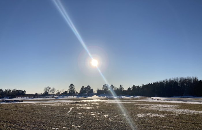 Solig vinterdag med snötäckt landskap och klarblå himmel.