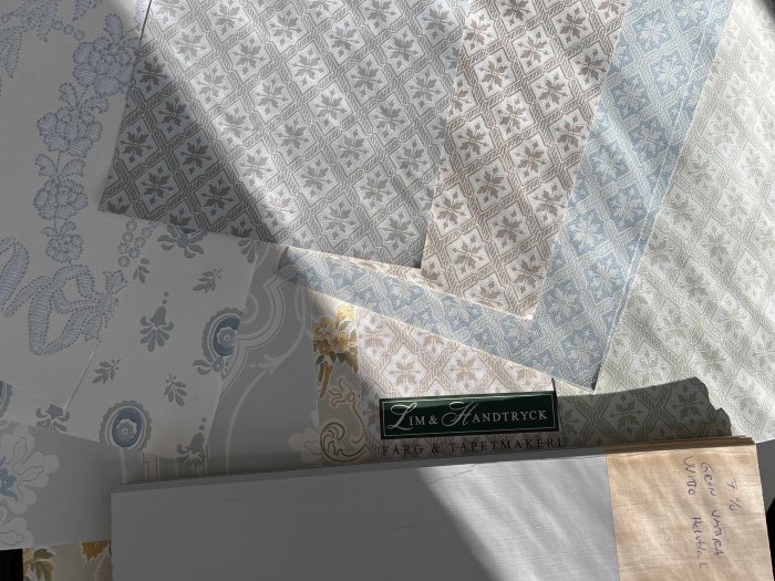 Olika prov av traditionella papperstapeter från Lim & Handtryck i solljus.