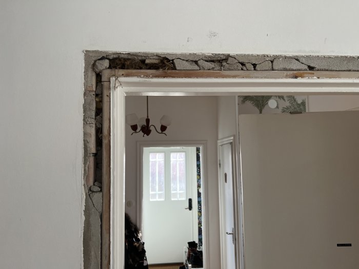 Skadat bruk mellan dörrkarm och tegelvägg i sekelskifteshus efter borttagning av gammalt dörrfoder.