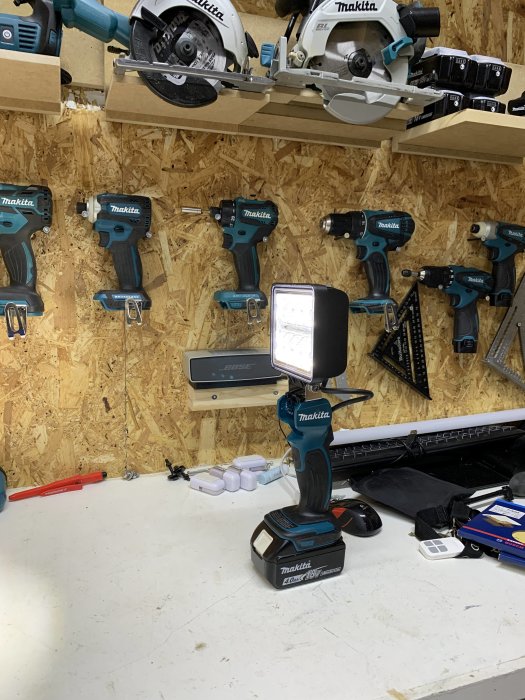 DIY LED-lampa monterad på ett Makita-batteri med buntband, placerad på arbetsbänk i verkstad.