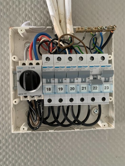 Öppen normcentral med säkringar, kablar och en huvudströmbrytare monterade på vägg.