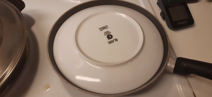 Rösti som steks i panna täckt med en tallrik för att vändas, i processen att tillagas.