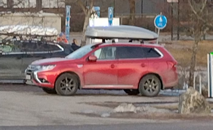 Röd bil parkerad med en takbox monterad bakåtvänt.