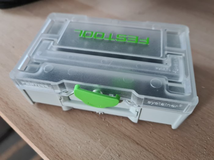 Plastbitsbox med märket "Festool" och grön låskläpp på grått underlag.