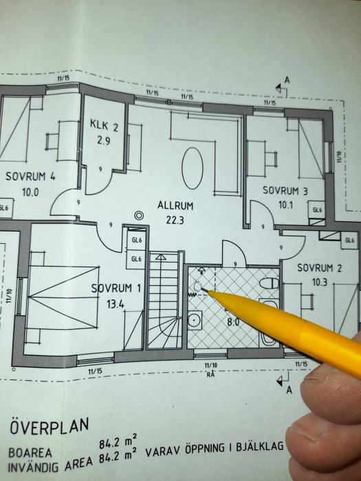 Hand som håller en penna pekande på en detalj i en arkitektonisk ritning av ett husöverplan med markerad cc60.