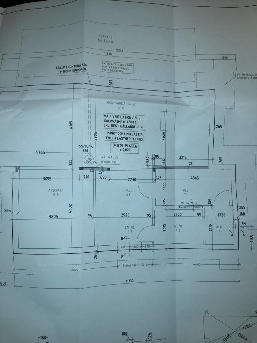 Arkitektonisk ritning av en byggnadsplan med markerade mått och beteckningar för rum som kök och vardagsrum.