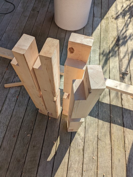 Fyra tillsågade träben redo för montering på trägolv i solljus, med verktygsspår synliga.