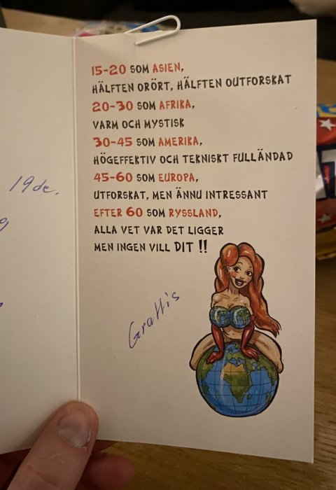 Öppnat gratulationskort med handskriven text och illustration av en tecknad kvinna sittande på en glob.