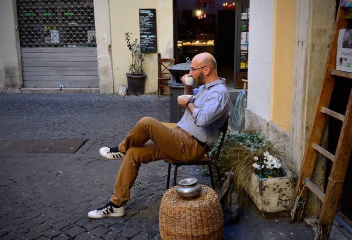 Man sitter avslappnat och dricker kaffe utanför en italiensk lägenhet.