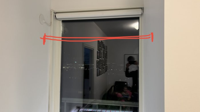 Inomhusfoto av ett hörn över ett fönster med en illustrativ röd linje där en vägghylla ska installeras.