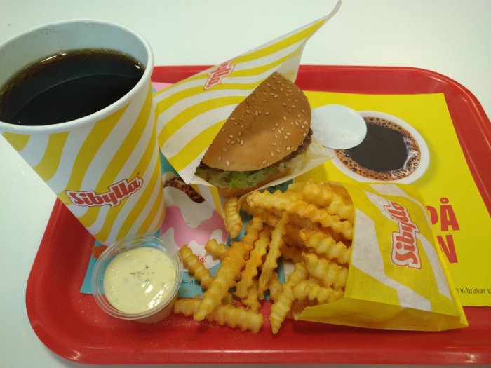 Hamburgare med pommes och läsk på bricka från snabbmatskedjan.