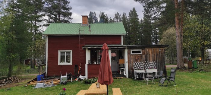 Rödmålat hus med grön plåttak och angränsande uterum och carport som ser asymmetriskt ut.