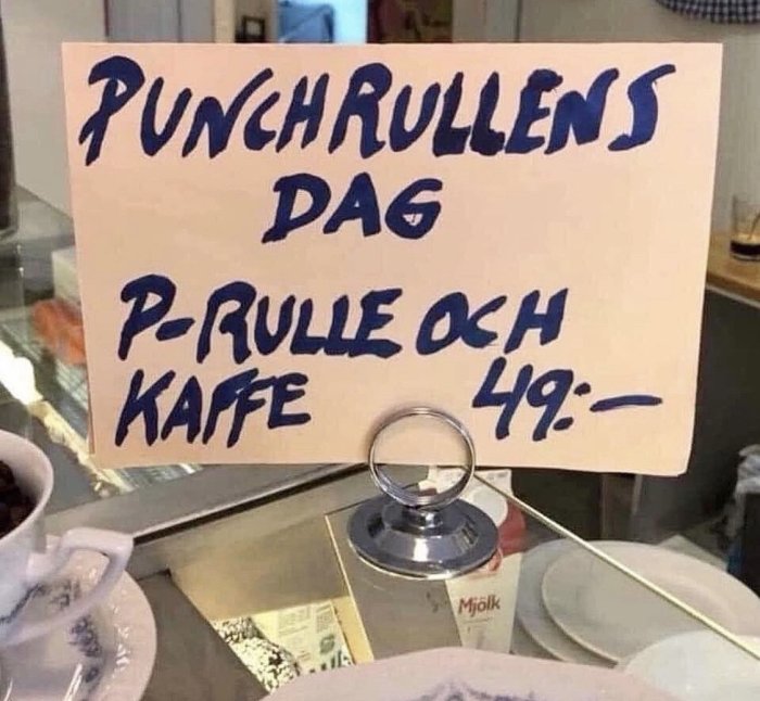 Skylt med texten "PUNSCHRULLENS DAG P-RULLE OCH KAFFE 49:-" på en cafédisk.