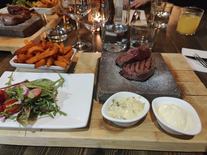 Stekt hjort och ren serverad på het sten med sallad, sötpotatisfries och två såser.