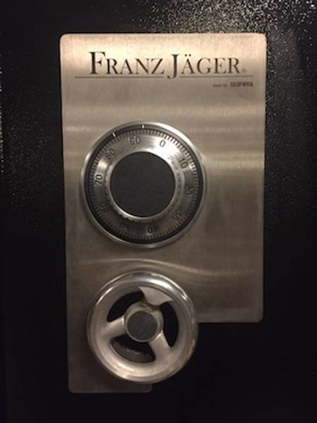 Ett kombinationslås på en kassaskåpsdörr med texten "Franz Jäger" och en treuddig symbol.