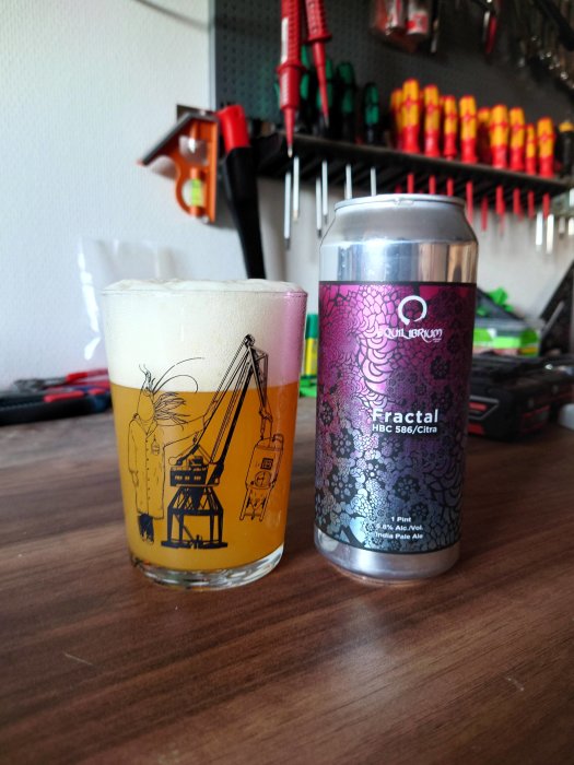 Ett glas med IPA-öl bredvid en Equilibrium Fractal burk med verktyg i bakgrunden.