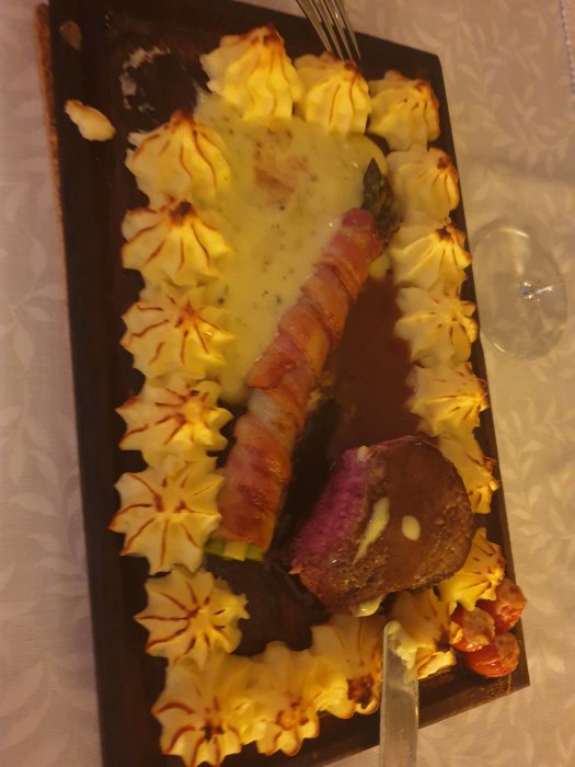 Älgstek med bacon och duchessepotatis serverad på träbricka, felaktigt trodd vara oxfilé.