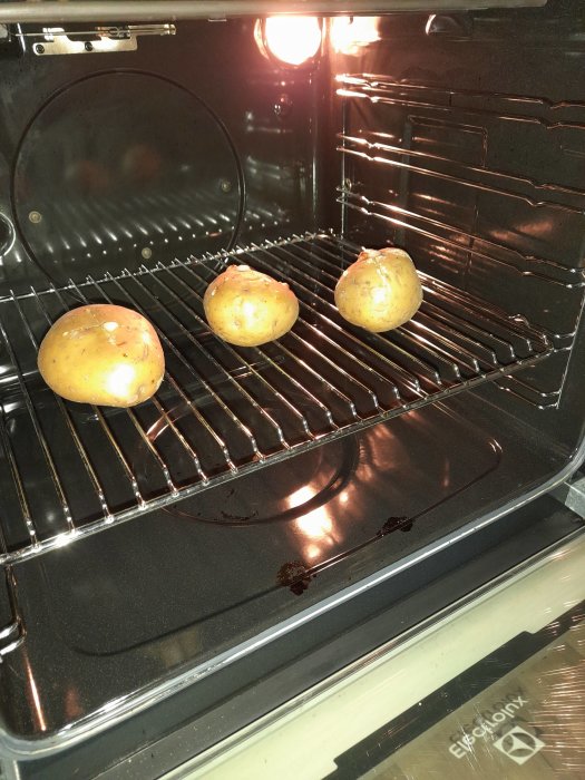 Tre bakpotatisar i en ugn nära att vara klara för servering med räkröra.