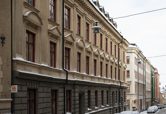 Snöklädd stadsgata med klassiska byggnader och en traditionell gatlykta, reflekterar belysning från 1986.