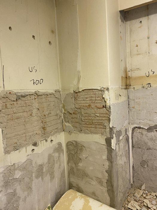 Ojämn vägg med spackel, murbruk och exponerade tegelstenar redo för renovering.