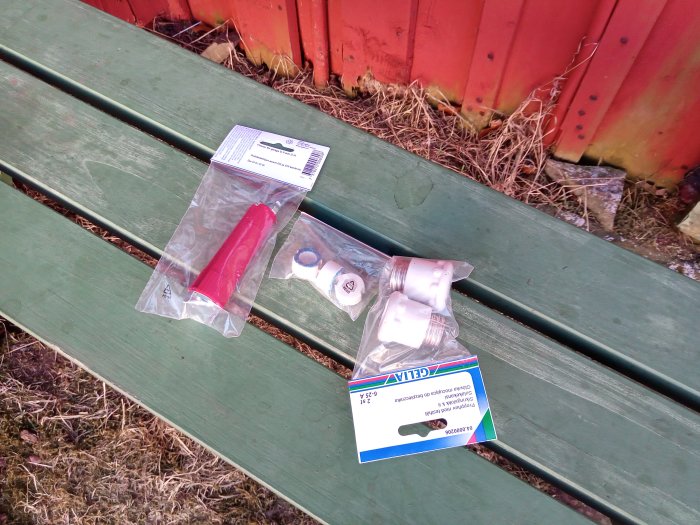 En äldre modell vit porslinsbrytare och dess förpackning på en grön bänk mot bakgrund av ett rött staket.