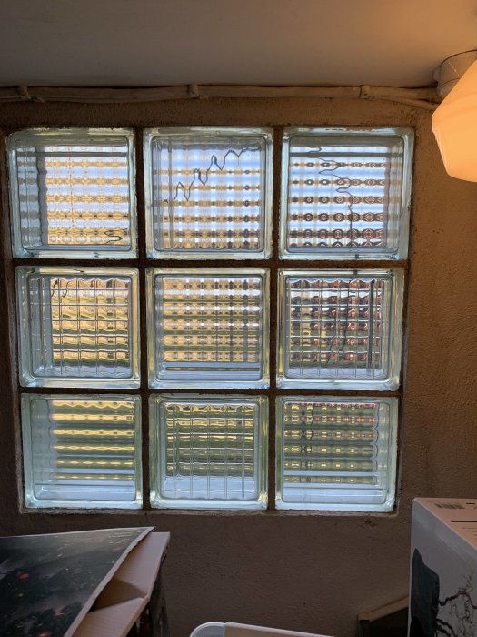 Väggen med nio glasblocksfönster som delvis släpper igenom ljus, fråga om byte till vanliga fönster.