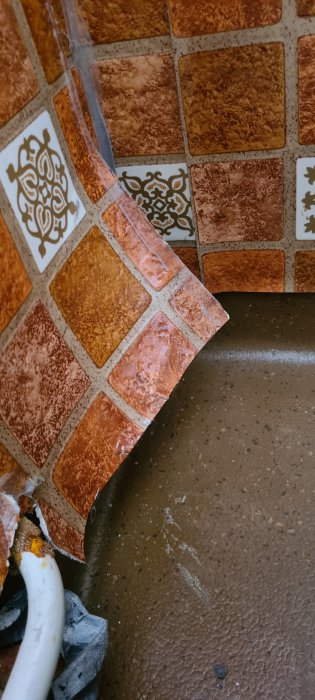Gammal sliten våtrumsmatta delvis lossnat från golvet med synliga limrester, en del i ett äldre badrums renoveringsprojekt.