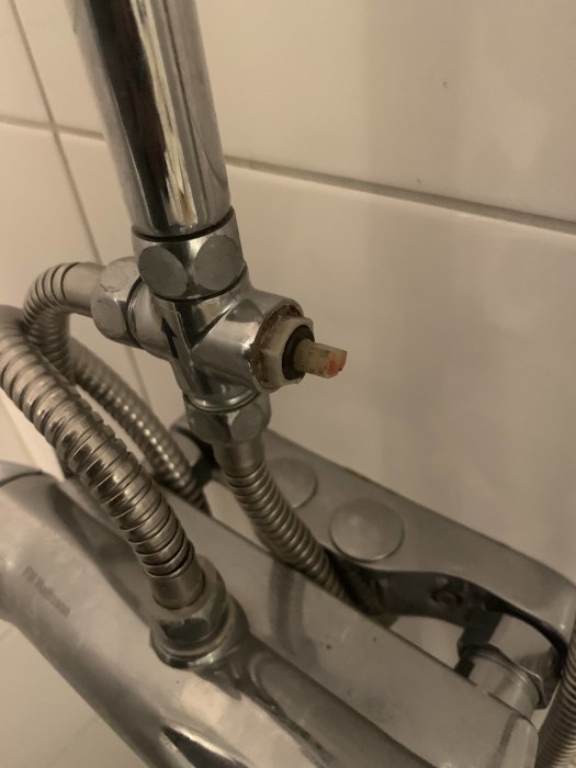 Duschkran utan vred monterad på kakelvägg, vattenvägar syns.