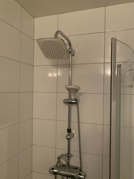 Duschsystem i badrum med övre och handhållen dusch, utan synligt vred.
