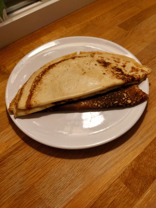 En tallrik med nygjorda pannkakor på ett träbord, en pappa lagar barnens önskemål.