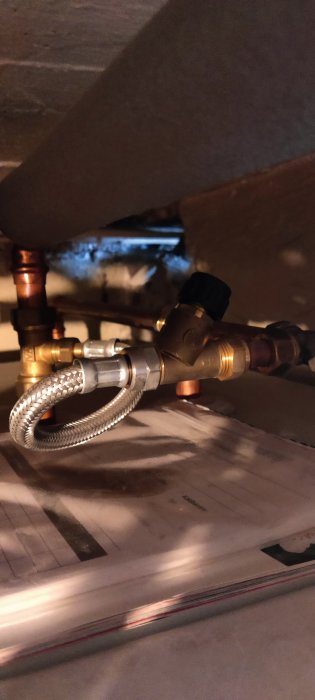 Kran för att fylla på tryck i värmesystem, monterad på kopparledning med flexibel anslutningsslang.