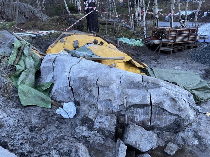 Bergsknalle täckt med presenningar och avspärrat område under bergspräckningsprocess.