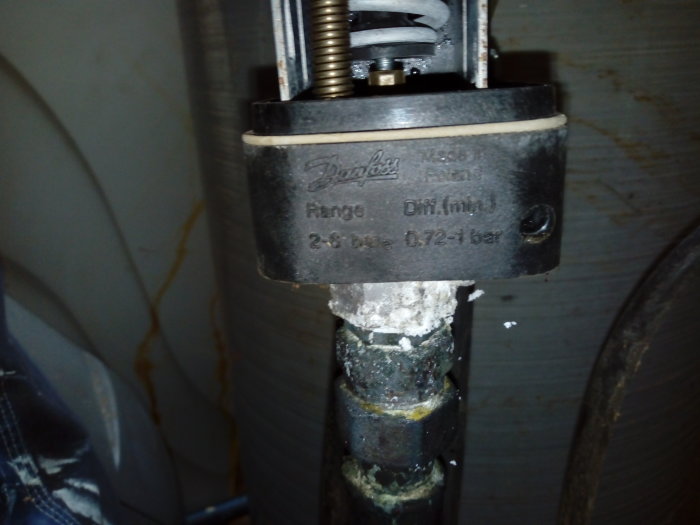 Närbild på ett äldre Danfoss pumprelä med inställningar som visar tecken på slitage och eventuell kalkuppbyggnad.