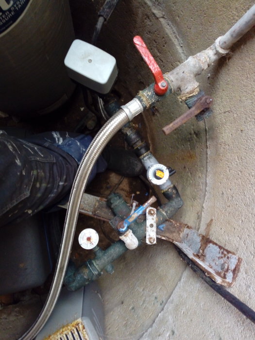 VVS-installation med pumprelä, manometer och röranslutningar i trångt utrymme.