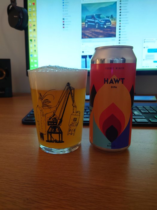 Ett glas öl med byggtema och en ölburk med texten "HAWT" framför en skärm med byggbilder.