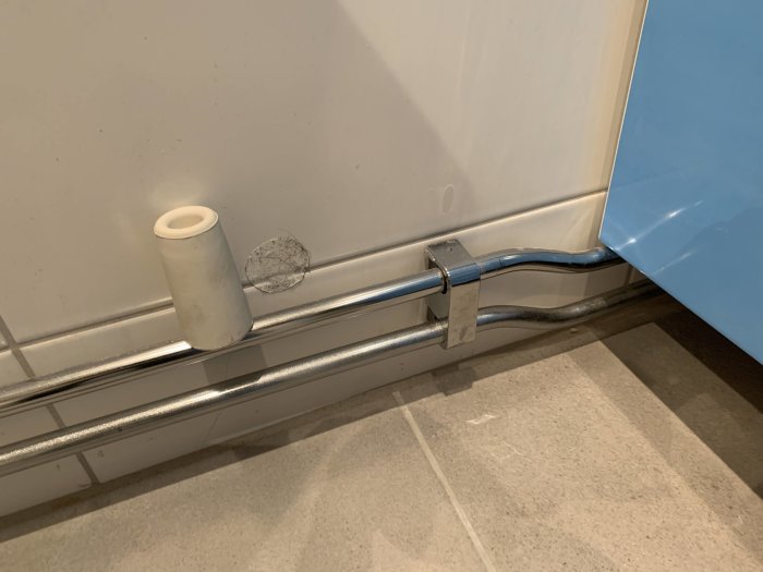 Rördragning under badrumsskåp med böj som hindrar full dörröppning och nöter på röret.
