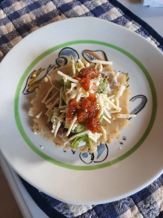 Hemgjord majstortilla med guacamole, sallad, tomat, ost och Aji-sås på en tallrik.