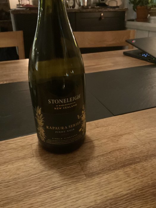 Flaska Stoneleigh Pinot Noir på träbord med suddig bakgrund av köksinteriör.