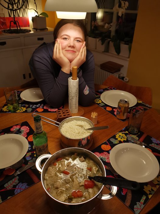 Ung kvinna poserar vid middagsbordet med en gryta Tom Kha Gai och ris.