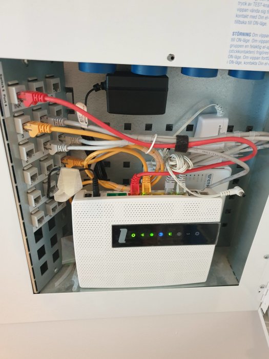 Öppen nätverkscentral med trassliga Ethernet-kablar, patchpanel och lysande switch.