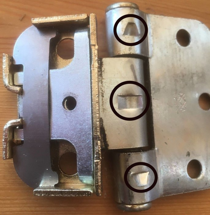 Närbild på delade dörrgångjärn med markerad mittersta skruv och nyptappar.