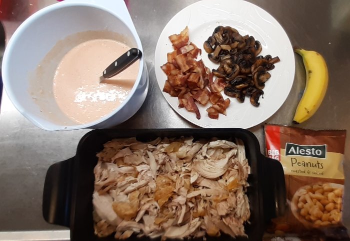 Ingredienser för Flygande Jakob: Ugnstekt kyckling i form, stekt bacon, champinjoner, banan, jordnötter, såsskål.