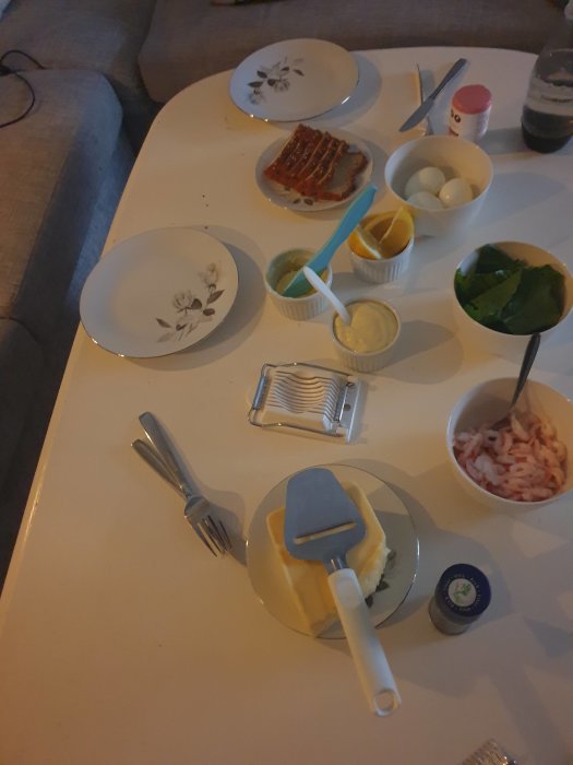 Ingredienser för macka utspridda på bord inklusive räkor, majonnäs, ägg och citron.