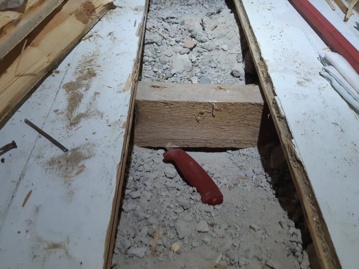 En bild på upptagen parkett och träreglar med murbruk och murbruksfyllning på ett golv under renovering.